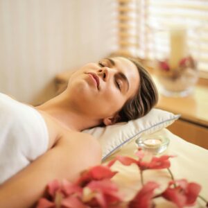 Woman enjoying a relaxing spa day with flowers and candles indoors.
